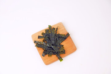 Crunchy seaweed rests on a wooden board. Clean, minimalist background highlights texture and color. Ideal for healthy food, wellness, or Asian cuisine visuals. No people, no animals, no plants © Nurma