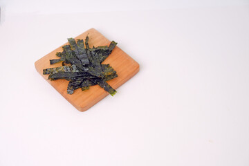 Crunchy seaweed rests on a wooden board. Clean, minimalist background highlights texture and color. Ideal for healthy food, wellness, or Asian cuisine visuals. No people, no animals, no plants © Nurma