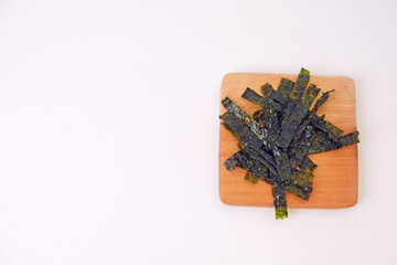 Crunchy seaweed rests on a wooden board. Clean, minimalist background highlights texture and color. Ideal for healthy food, wellness, or Asian cuisine visuals. No people, no animals, no plants © Nurma