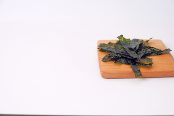 Crunchy seaweed rests on a wooden board. Clean, minimalist background highlights texture and color. Ideal for healthy food, wellness, or Asian cuisine visuals. No people, no animals, no plants © Nurma