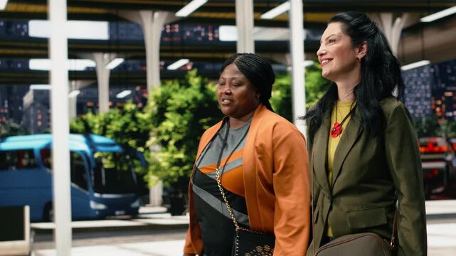 Friends enjoy a fun discussion while moving across the bus station platform with bags, talking and walking together through the intercity coach terminal as they leave on a vacation journey.