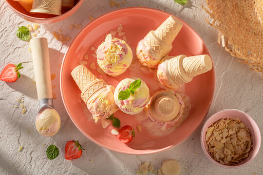 Cold and homemade strawberry ice cream in a waffle cone.