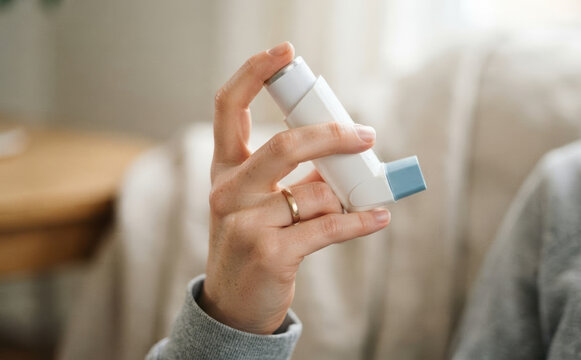 Woman holding an asthma inhaler in her hand for respiratory relief and allergy treatment