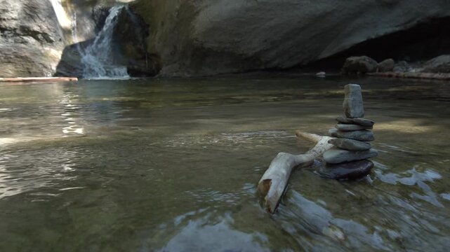 Zen Steine Stapel im fliessend Gew&auml;sser mit Wasserfall im Hintergrund - Natur und Entspannung