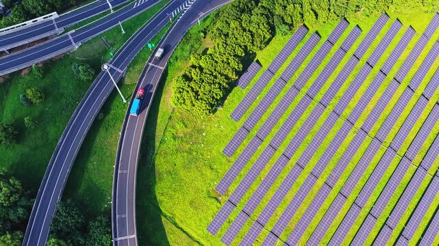 Top down drone tracking shot of solar panels and a curved highway