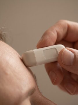 Close up of a person getting their temperature taken with a modern digital forehead thermometer