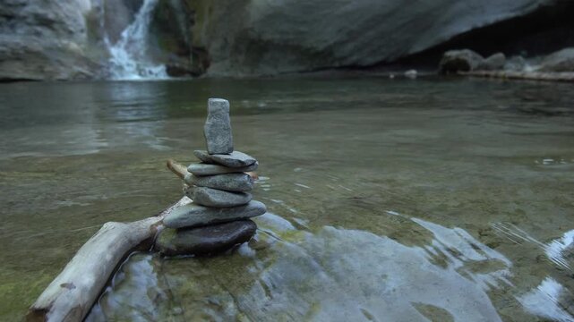 Zen Steine Stapel im fliessend Gew&auml;sser mit Wasserfall im Hintergrund - Natur und Entspannung