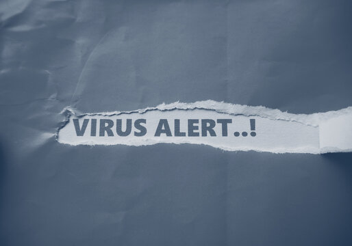 Virus alert written under torn grey paper. Virus threat warning message behind torn paper.
