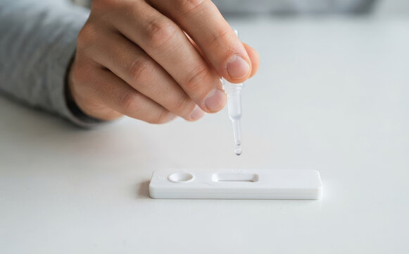 Close up of a person using a rapid antigen self test kit at home for health diagnosis