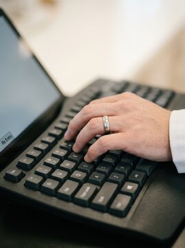 Close-up of a male pharmacist typing prescription data on a keyboard in a pharmacy