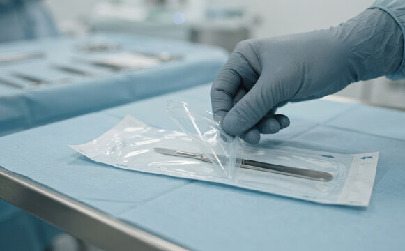 Medical professional opening a sterile scalpel package in a hospital operating room for surgery