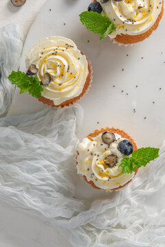 Cupcakes with cream frosting blueberry and mint leaves on a white surface top view