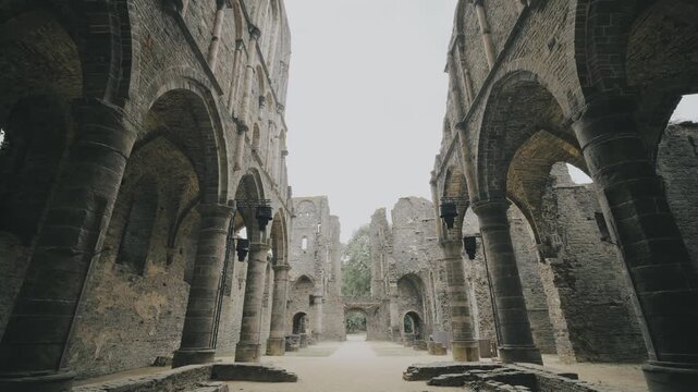 Majestic gothic arches and towering stone walls of the ruined medieval Villers Abbey church in Belgium.