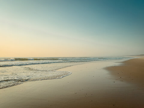 Serene sandy ocean beach horizon view at sunset time