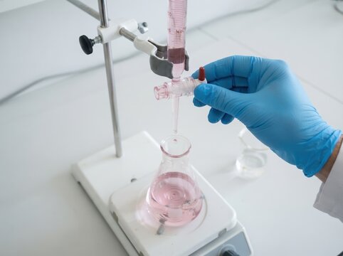 A scientist performing a chemical titration experiment in a laboratory using a burette and flask
