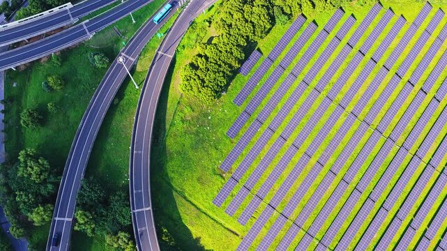 Aerial overhead view moving along solar panels and highway lanes