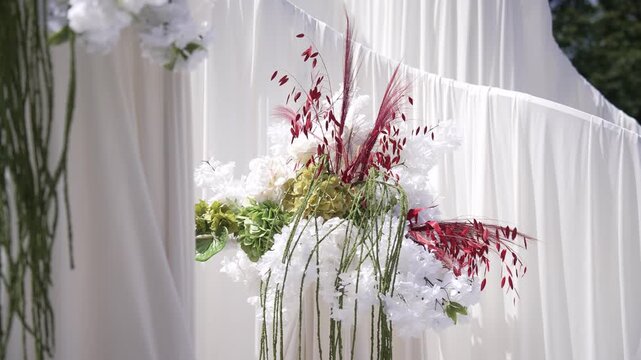 Close-up of an elegant wedding floral arrangement with hydrangea and pampas grass behind a sheer white fabric drape.