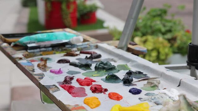 Woman artist paint picture with oil colors on canva in the park during sunny day