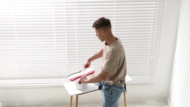 Worker taking plaster with putty knife near console table and white wall indoors