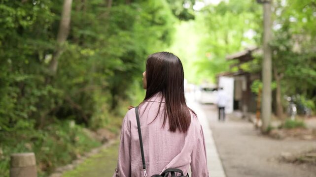 東京のレトロな観光地（深大寺近くの公道）を散策する女性の後ろ姿のフォローショット