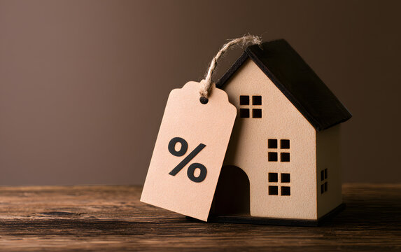 A miniature house featuring a percentage tag symbol, which illustrates mortgage interest rates and real estate investment