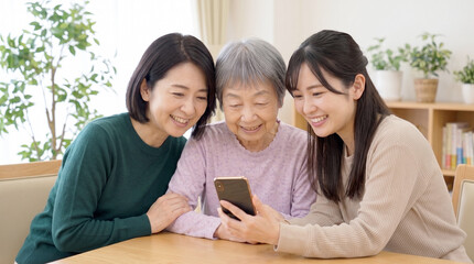 Obraz premium スマートフォンを見ながら笑顔で過ごす祖母と家族