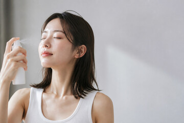 Obraz premium 顔にミスト化粧水を吹きかける日本人女性 美容 Generative AI