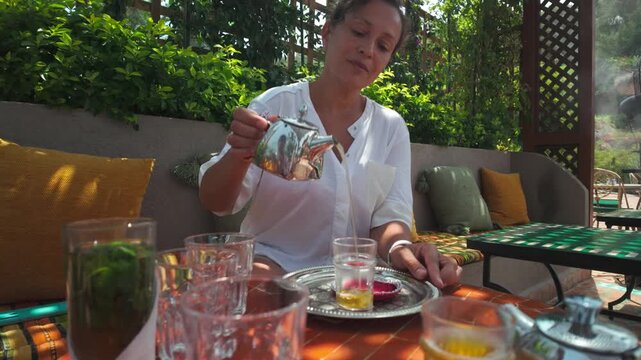 Woman Pouring Traditional Moroccan Mint Tea Outdoors in Tangier, Morocco