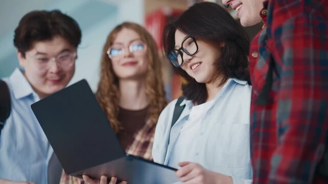 Students collaborate on laptop in classroom with diverse group focusing on learning task