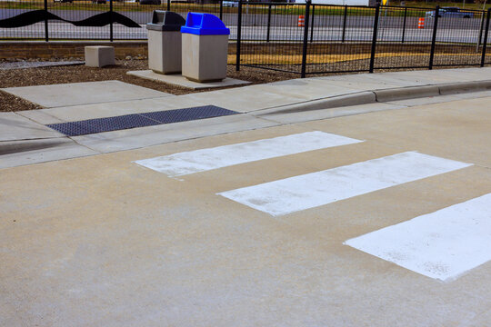 People are walking in parking lot with crosswalk trash bins visible.