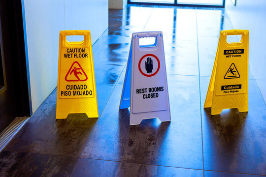 Signs alerting people about wet floors, closed restrooms in building visitors need to be cautious aware.