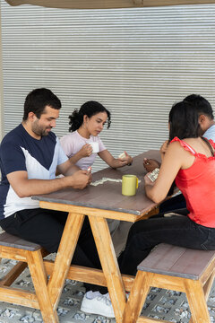 Young adults playing dominoes game outdoors with friends