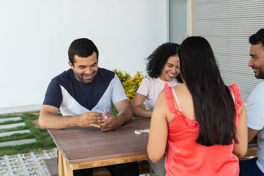Young adults playing dominoes at outdoor social gathering