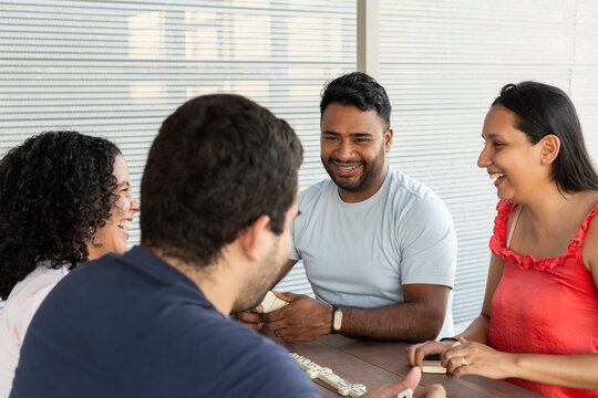 Young adults laughing playing dominoes board game