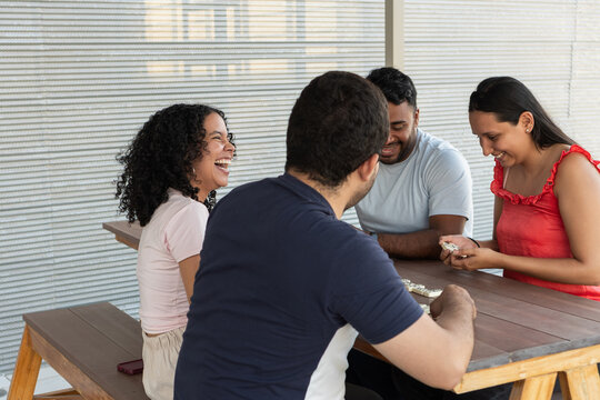 Young adults laughing while playing dominoes outdoors