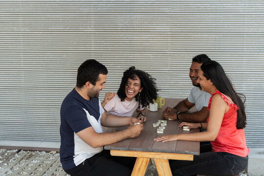 Young adults playing dominoes laughing having fun