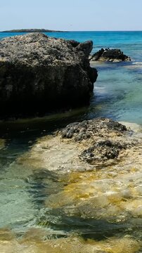 Vertical video of Elafonisi beach with pink sand and black rocks. Crete. Greece