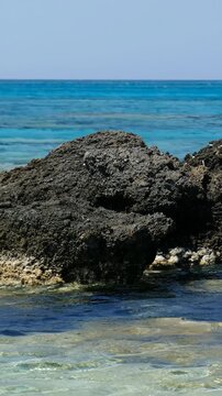 Vertical video of Elafonisi beach with pink sand and black rocks. Crete. Greece