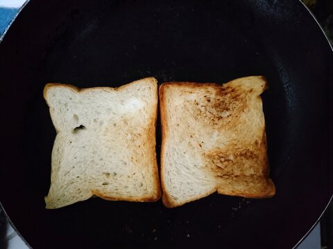 Two Slices of Bread Toasting in a Black Pan.