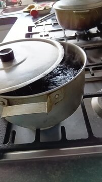 Una olla vieja con agua hirviendo con vapor  en una cocina de una casa. Video vertical