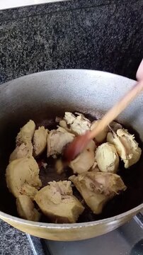 Una toma de cerca de un sart&eacute;n en donde se encuentra trozos de pollos ricos  cocinando con aceite y saliendo vapor. Estilo de vida. Video vertical  