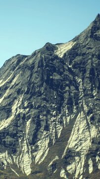 A tall, rugged mountain rises against a brilliant blue sky. Striking layers of rock reveal natures artistry.