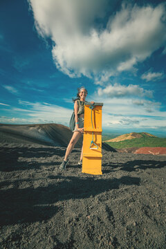 Smiling female tourist holding a sandboarding board on Cerro Negro. Portrait of smiling girl on the Cerro Negro volcano holding a sandboarding board