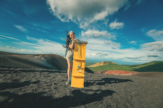 Portrait of smiling girl on the Cerro Negro volcano holding a sandboarding board. Smiling female tourist holding a sandboarding board on Cerro Negro