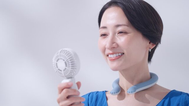 夏にアイスリングとハンディ扇風機を使う女性