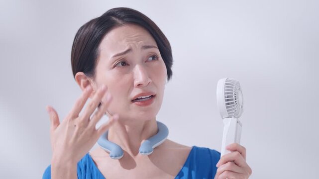 夏にアイスリングとハンディ扇風機を使う女性
