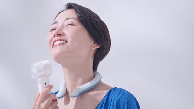 夏にアイスリングとハンディ扇風機を使う女性