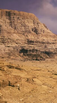 Rugged cliffs rise dramatically from the dry earth, creating a striking contrast against a colorful sky. The serene beauty of this desert scenery invites exploration and wonder.