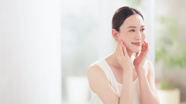 ほほに手を当てて素肌の保湿を確認する綺麗な日本人女性