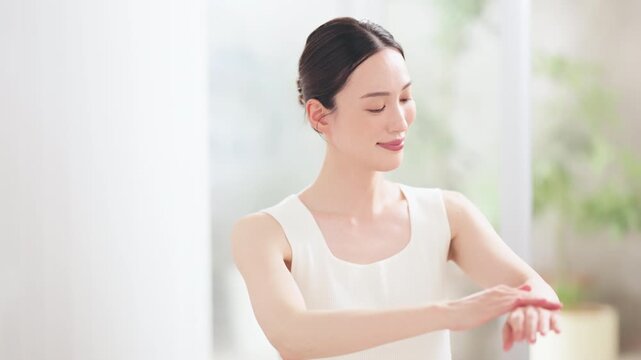 腕にボディクリームを塗って保湿ケアをする笑顔の女性